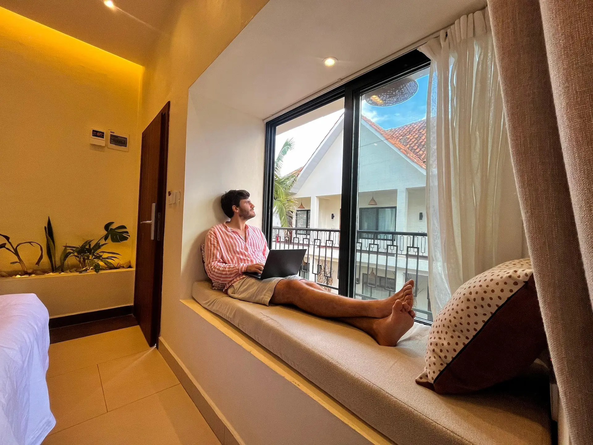Guest working on window seat with laptop overlooking courtyard