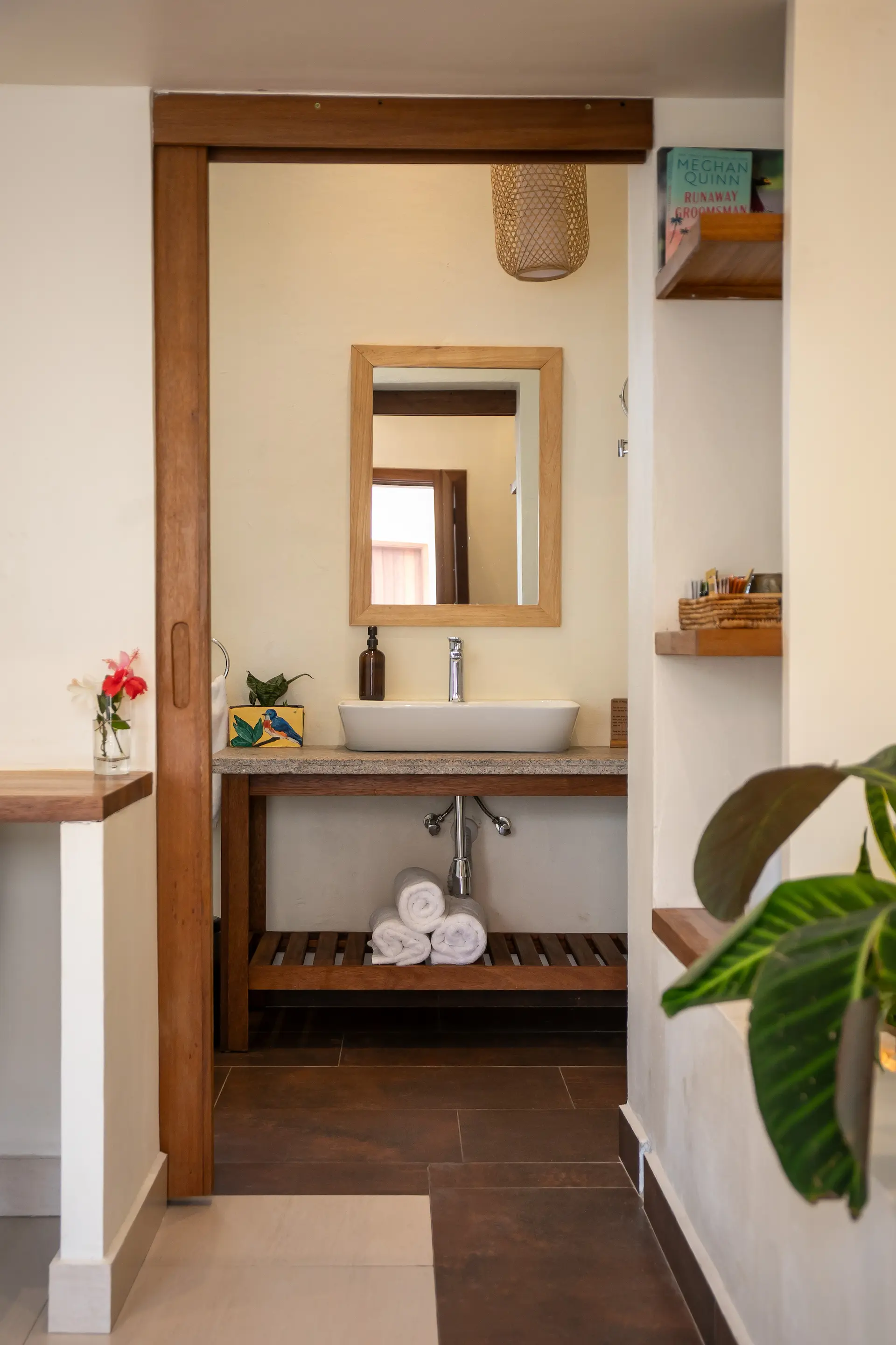 En-suite bathroom with vessel sink, wooden sliding door and bamboo pendant
